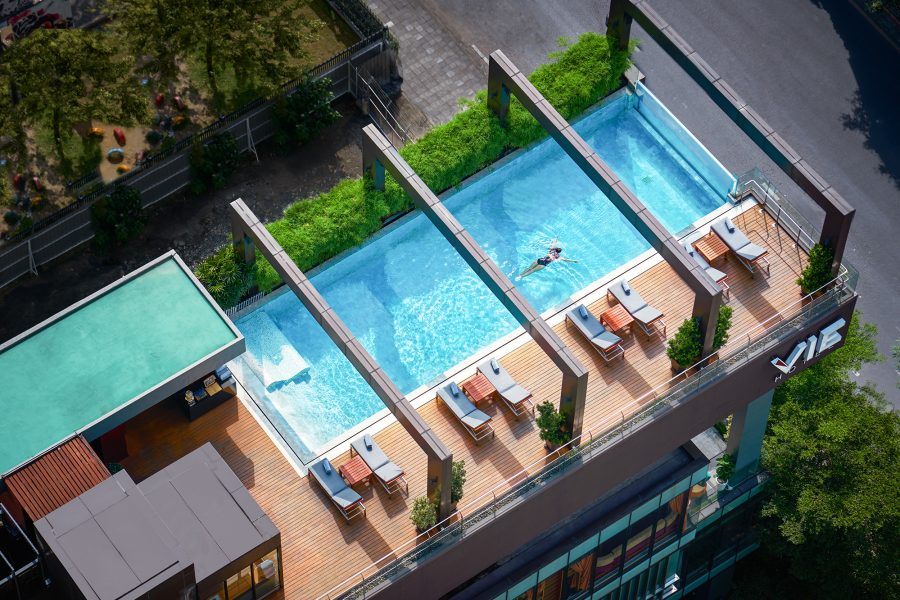 Aerial view of a rooftop swimming pool at VIE Hotel Bangkok - MGallery, showcasing city skyline and blue water.